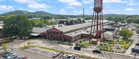 En parkeringsplats med flera bilar, en byggnad med en skylt som visar texten ”Dortch Stove Works”, och ett högt vattentorn med texten ”The Factory Franklin”.