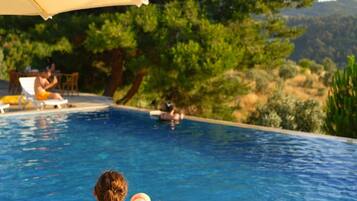 Una piscina con vistas despejadas del paisaje circundante, incluyendo árboles y colinas.