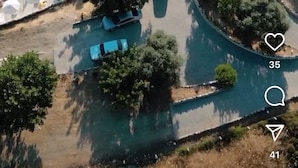 Vista aérea de una zona residencial con una piscina, una casa pequeña y un coche aparcado cerca.