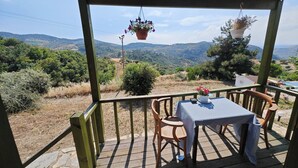 Un espacio de estar al aire libre con techo, con una mesa y sillas, con vistas a un paisaje montañoso.