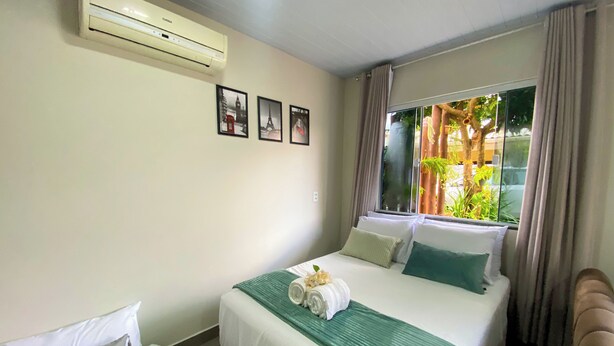 Hotelkamer met een bed, een bijzetbed, een airconditioner en een raam met gordijnen.