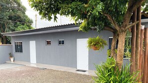 Een modern huis met een grijze gevel, witte luiken en een grindpad.