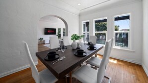 Ein Essbereich mit einem dunklen Holztisch, weißen Stühlen und einem modernen Interieur.