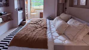 Une chambre à coucher avec un lit, une chaise, un bureau et une vue sur l’extérieur.