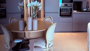 Une cuisine moderne avec un coin repas, comprenant une table ronde avec des chaises, un four à micro-ondes, un four et un réfrigérateur.