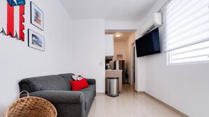 Un salon moderne avec un canapé gris, un panier en osier et un téléviseur à écran plat fixé au mur.