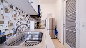 Une cuisine compacte dotée d’un évier en acier inoxydable, d’un four encastré et d’un réfrigérateur.