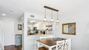 A modern kitchen with white cabinets, a built-in oven, and a hanging light fixture.