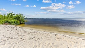 A beach with clear water, a sandy shore, and a distant horizon.