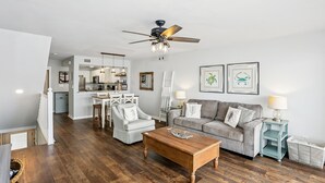 A modern living room with a wooden coffee table, grey sofa, and a ceiling fan.