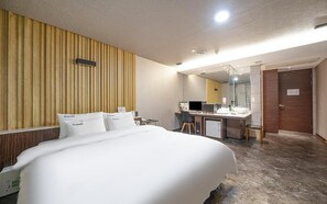 A hotel room with a bed, a desk, a chair, a mirror, and a door. - YEONGJU SPA TOURIST HOTEL (Yeongju)
