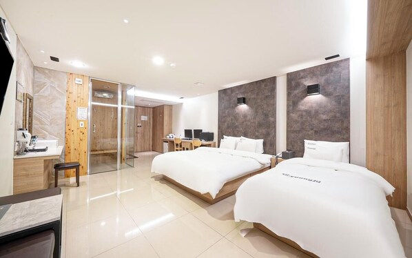 A modern hotel room with two beds, a desk, a chair, and a bathroom with a mirror and sink. - YEONGJU SPA TOURIST HOTEL (Yeongju)