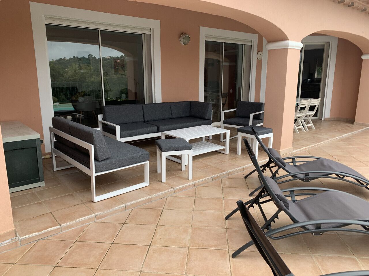 Un patio al aire libre con un conjunto de sofá, una mesa de centro y dos sillones.
