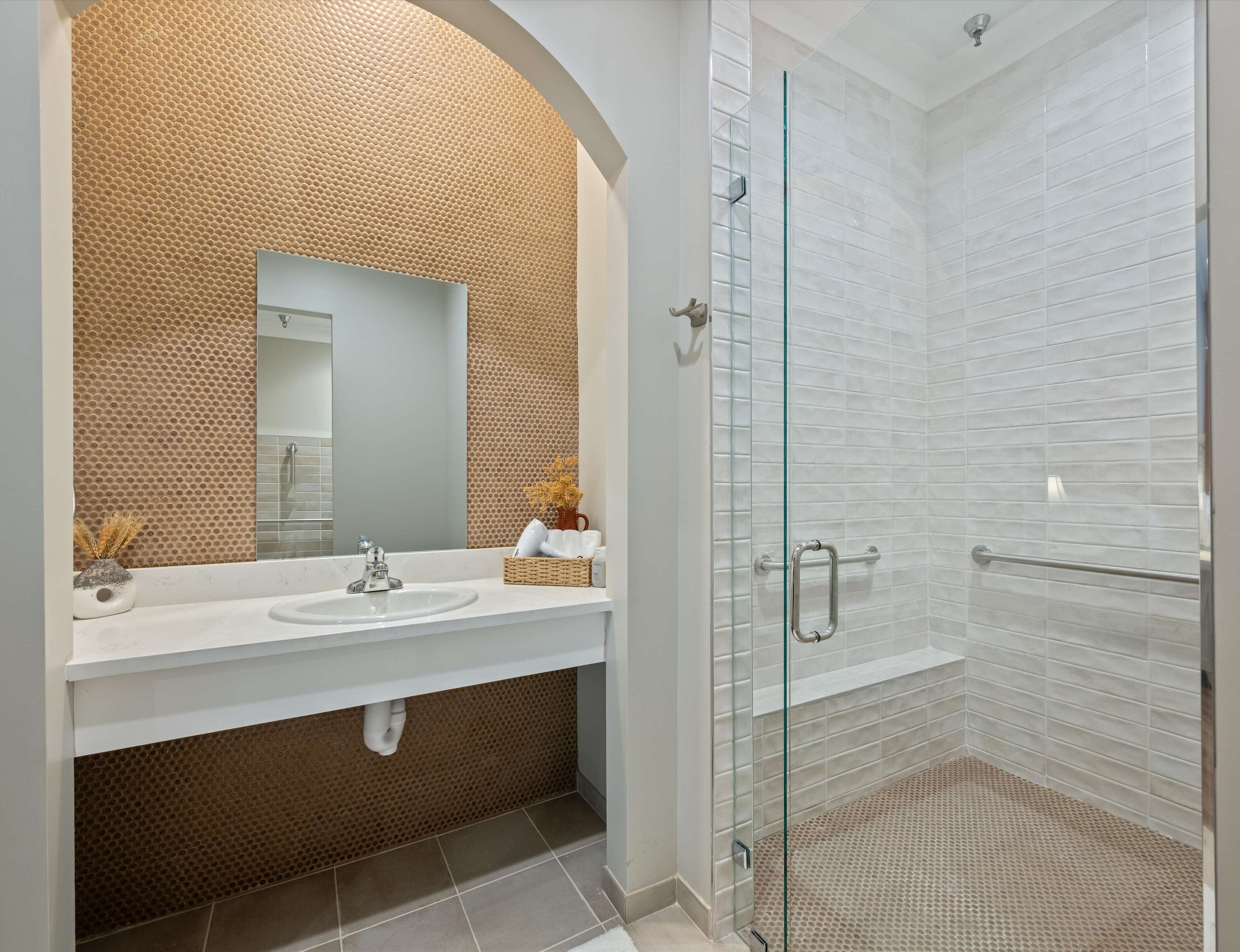 Un baño con un lavamanos blanco, un espejo grande y una ducha con puerta de cristal.