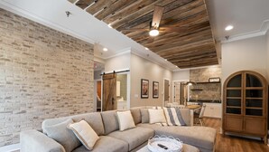 A modern living room with a sectional sofa, a wooden ceiling, and a brick wall. - Carters Court Grand Escape (Franklin)