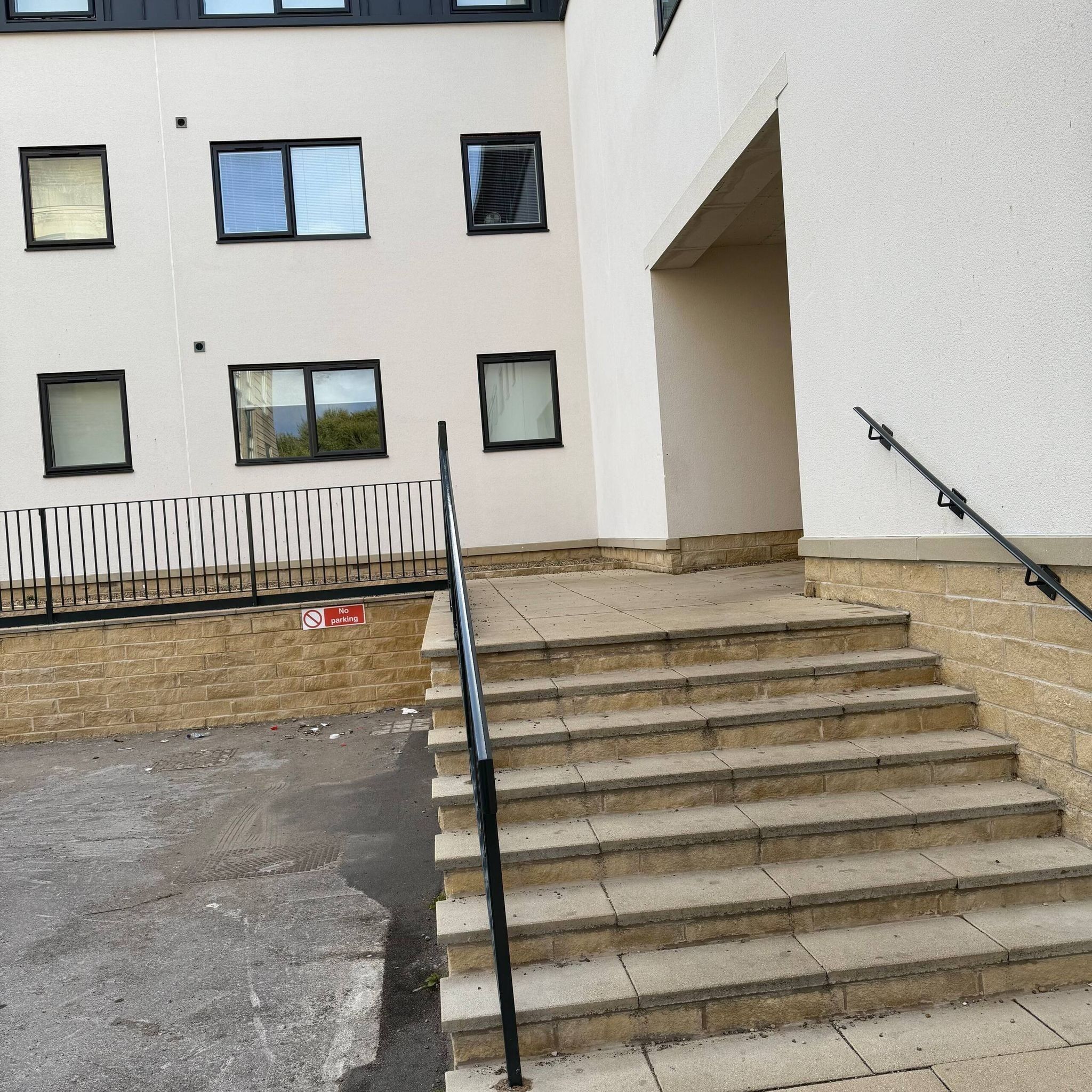 Un bâtiment doté de nombreuses fenêtres, d’un escalier et d’un panneau indiquant « Stationnement interdit ».
