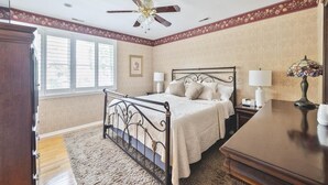 Ein Schlafzimmer mit einem Bett, Nachttischen, einem Deckenventilator und einem Fenster.