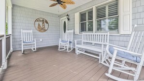 Eine überdachte Veranda mit weißen Schaukelstühlen und einem Deckenventilator.