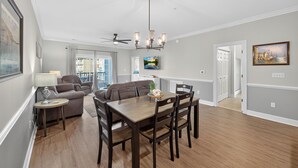 A spacious living area with a dining table, sofas, and a ceiling fan.