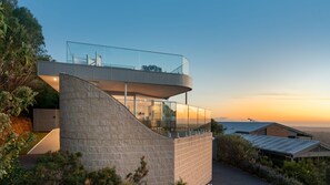 A modern house with a glass balcony, a stone staircase, and a view of the sunset. - Horizons on Hove with Heated Spa (Rosebud)