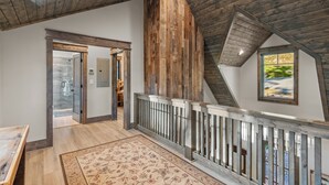 Un loft spacieux avec de hauts plafonds, des poutres apparentes et une vue sur un jardin, visible par une fenêtre.