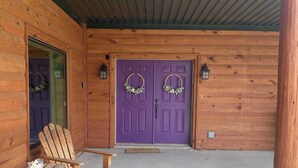 A wooden cabin with a purple door, two wooden chairs, and a concrete floor. - Redbud Honey - Country Cabin away from it all (Lone Grove)