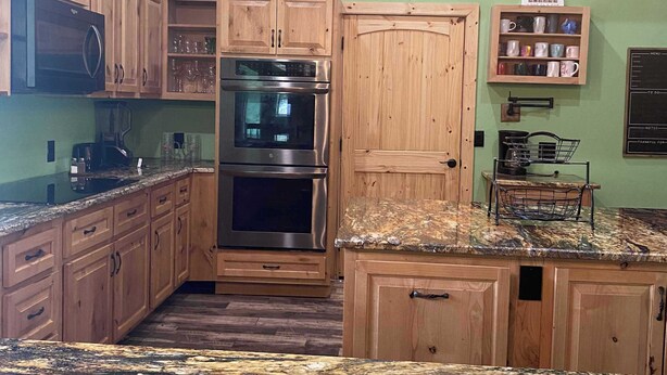 A kitchen with wooden cabinets, stainless steel appliances, granite countertops, and pendant lighting. - Redbud Honey - Country Cabin away from it all (Lone Grove)