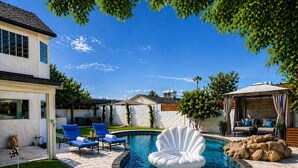A backyard with a swimming pool, lounge chairs, a covered seating area, and a decorative shell. - Modern Scottsdale Oasis Near Old Town–Pool, Waterfall, Glam Room & Putting Green (Scottsdale)
