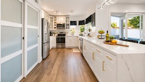 A modern kitchen with white cabinetry, stainless steel appliances, and a marble countertop. - Modern Scottsdale Oasis Near Old Town–Pool, Waterfall, Glam Room & Putting Green (Scottsdale)