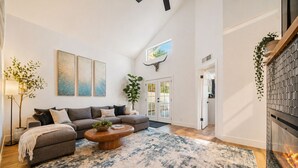 A modern living room with a sectional sofa, a wooden coffee table, and a large window. - Modern Scottsdale Oasis Near Old Town–Pool, Waterfall, Glam Room & Putting Green (Scottsdale)