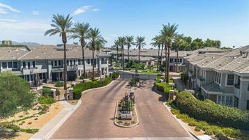 Una calle residencial con casas, palmeras y un acceso con portón.