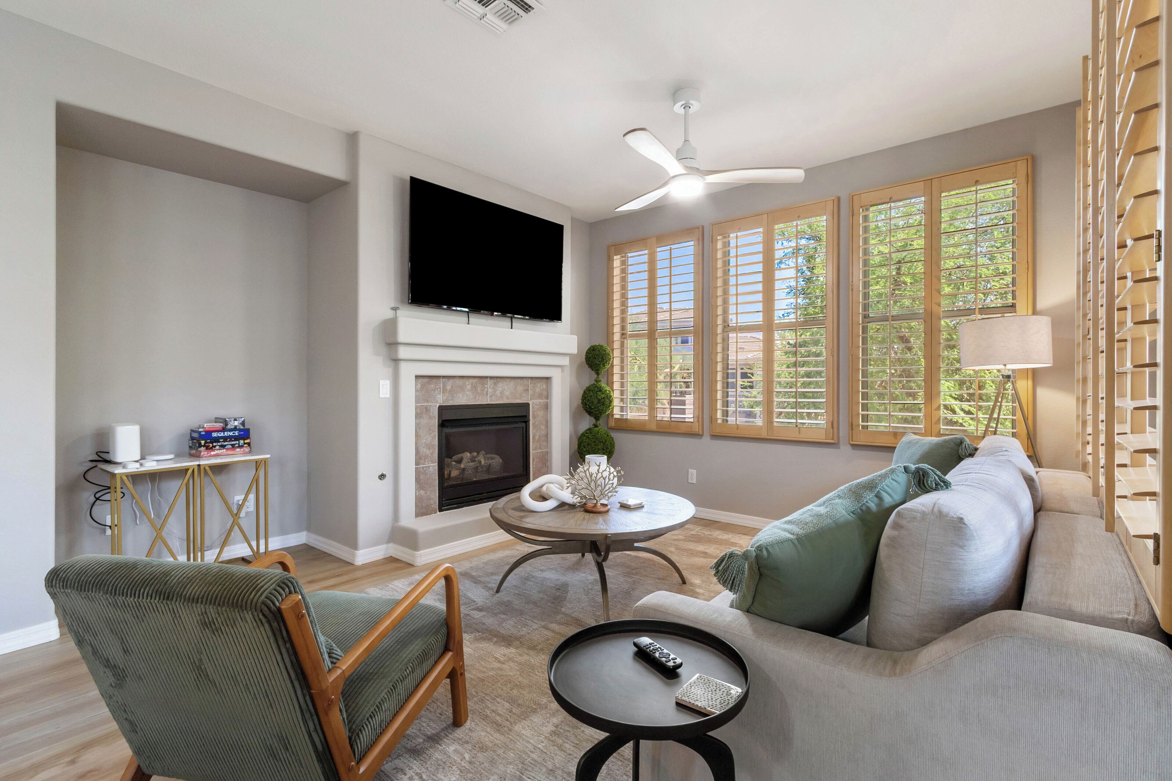 A living room with a fireplace, a sofa, a chair, a TV, and large windows.