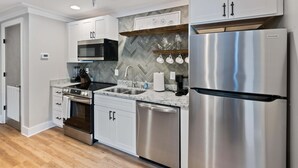 A modern kitchen with stainless steel appliances, white cabinetry, and a herringbone tile backsplash. - Carters Court Cozy Hideaway (Franklin)