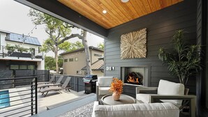 A modern outdoor living area with a pool, lounge chairs, a fire pit, and a view of neighboring houses. - Luxury Dual-Home Retreat w/ Pool in Austin’s Coveted downtown Travis Heights! (Austin)