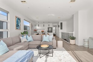 Ein modernes Wohnzimmer mit einer Eckcouch, einem Couchtisch und Blick zur Küche.