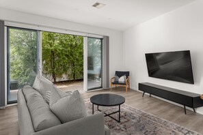 Een moderne woonkamer met een grote bank, een salontafel en een aan de muur bevestigde televisie.