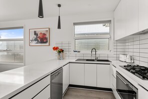 Une cuisine moderne avec des meubles blancs, un lave-vaisselle, un évier et une cuisinière.