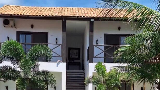 Una casa moderna con piscina, palmeras y una escalera que conduce a la entrada.