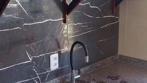 Una cocina con encimera de granito, un lavamanos, un microondas y una estantería con ollas.