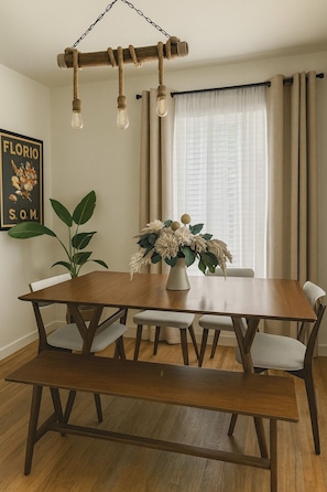 Uma área de refeições com mesa de madeira, bancos e luminária pendente.