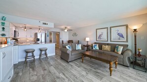 A spacious living area with a kitchen, a sofa set, and a coffee table. - Beachfront Condo Cabana Club 202 Beautiful Water Views& Private Beach Access (Destin)