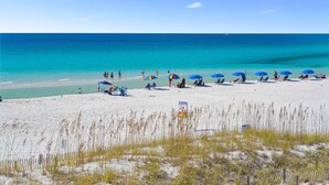 A beach with clear turquoise water, people relaxing under umbrellas, and a sandy shore. - Beachfront Condo Cabana Club 202 Beautiful Water Views& Private Beach Access (Destin)