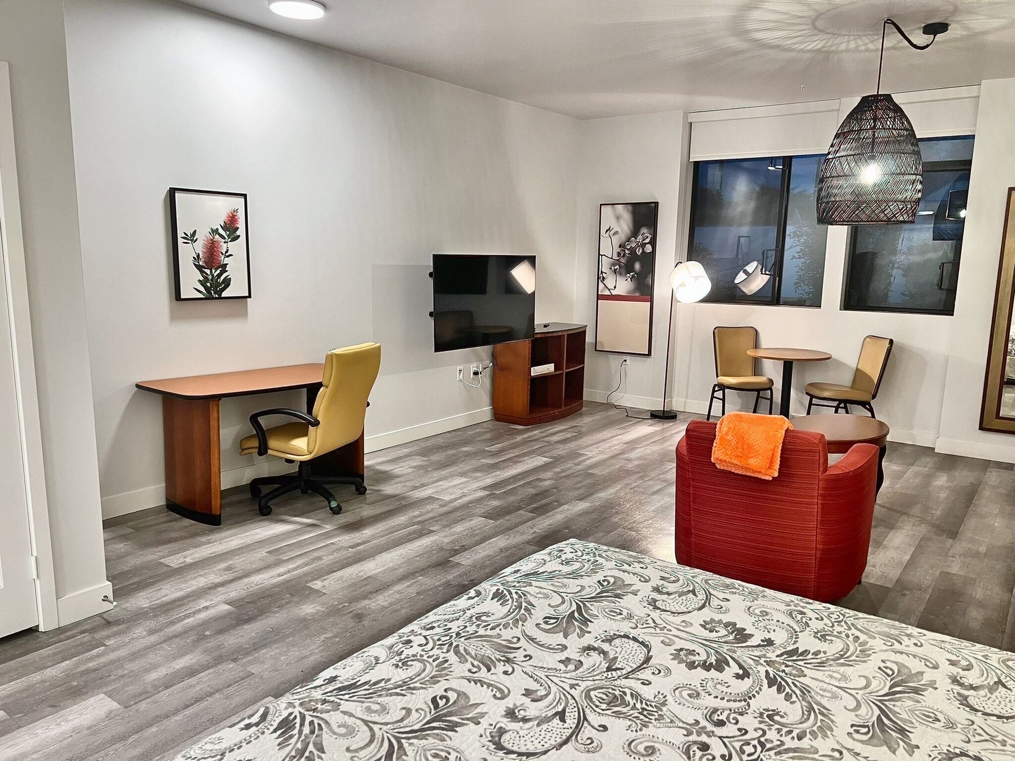 A modern room with a wooden desk, a red sofa, a patterned rug, and a television.