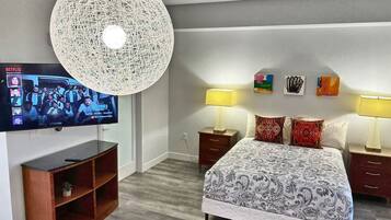 A modern hotel room with a large bed, two bedside tables with lamps, a TV mounted on the wall, and a decorative ceiling light.