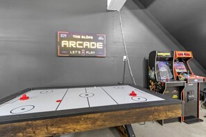 Eine Indoor-Spielehalle mit Shuffleboard-Tischen und klassischen Arcade-Automaten.