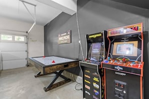 Una habitación con una máquina de juegos tipo arcade, dos máquinas de arcade y un cartel en la pared.