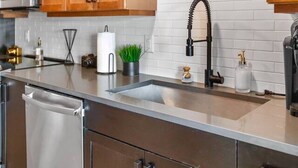 A modern kitchen with wooden cabinets, stainless steel appliances, and a white tiled backsplash. - Deep Ellum | 4 Ppl | Walkable | Great Views (Dallas)
