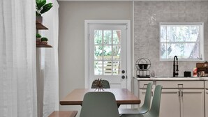 Une cuisine avec des meubles blancs, un plan de travail en bois et une fenêtre avec des stores.