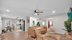 Un salon moderne avec un canapé, des fauteuils, une table basse et un ventilateur de plafond.