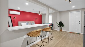 Eine moderne Küche mit roter Akzentwand, weißen Schränken und zwei Korbstühlen.